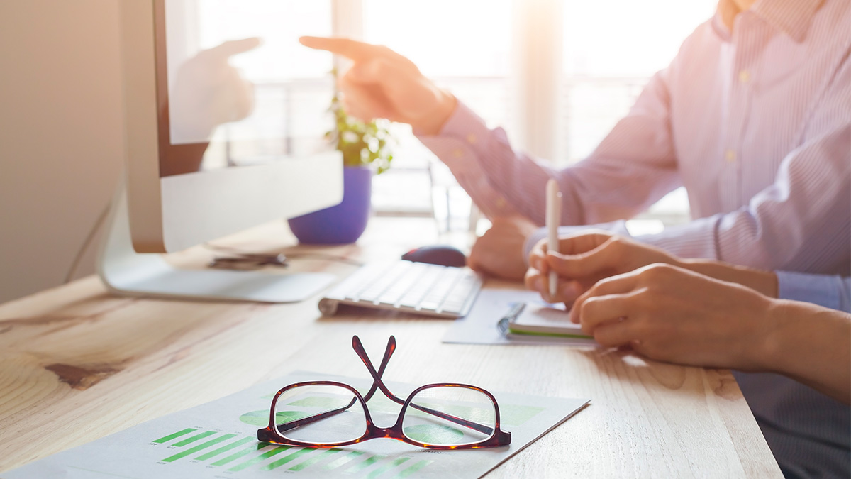 glasses sitting on desk while people work